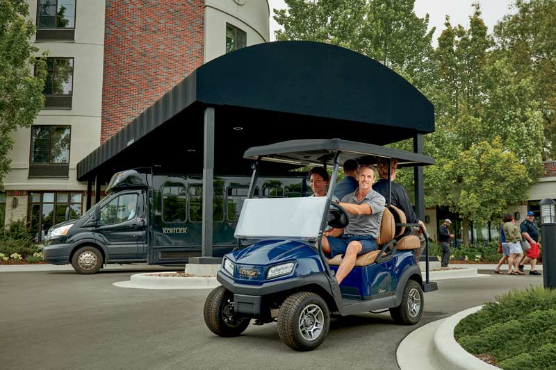 Golf cart driving past building entranc